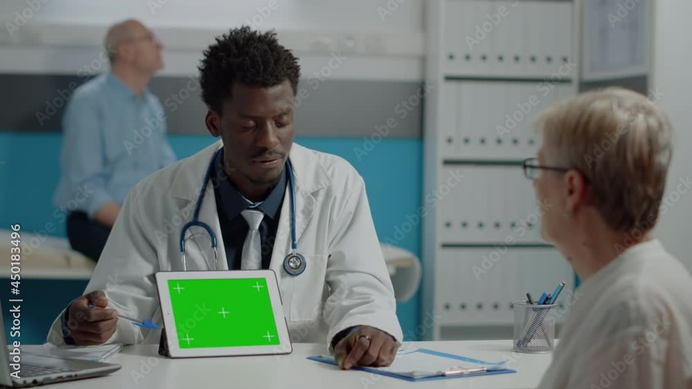 Man working as doctor pointing at green screen on modern tablet in office. Medic with horizontal mockup template and isolated chroma key technology for appointment at medical facility Man working as doctor pointing at green screen on modern tablet in office. Medic with horizontal mockup template and isolated chroma key technology for appointment at medical facility