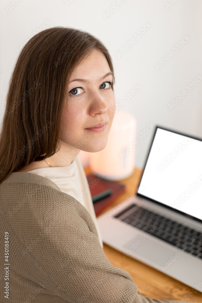 Calm caucasian woman tired of working at computer. Working from home office. Attractive brunette woman looking into camera. Selective focus. On the background empty blank white screen. Calm caucasian woman tired of working at computer. Working from home office. Attractive brunette woman looking into camera. Selective focus. On the background empty blank white screen.
