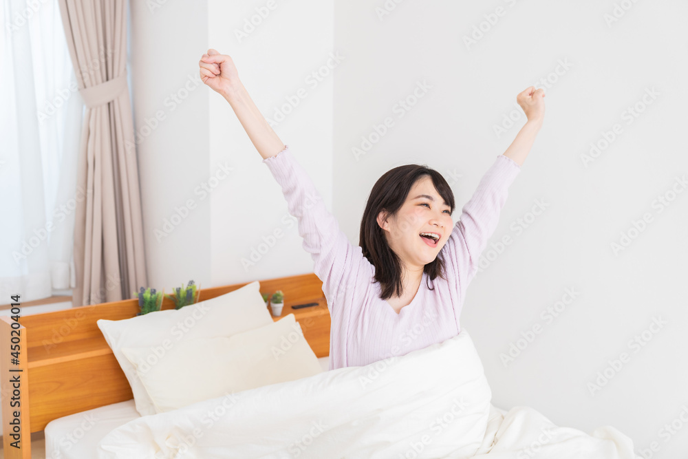 パジャマを着た女性 ベッド 笑顔 パジャマを着た女性 ベッド 笑顔