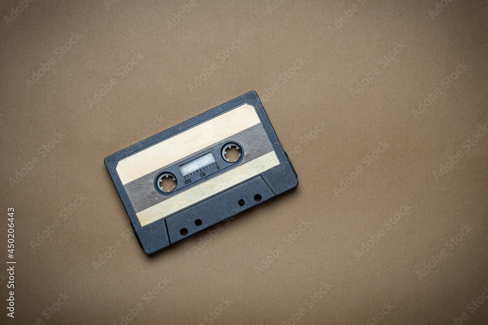 Old audio cassette on a brown background. Cassette for listening in an audio player or tape recorder. Old audio cassette on a brown background. Cassette for listening in an audio player or tape recorder.