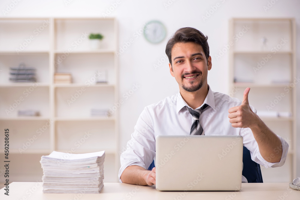 Young male employee unhappy with excessive work in the office Young male employee unhappy with excessive work in the office
