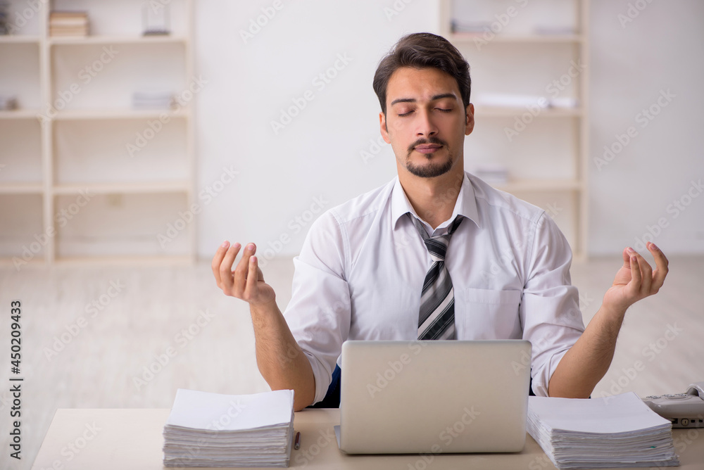 Young male employee unhappy with excessive work in the office Young male employee unhappy with excessive work in the office