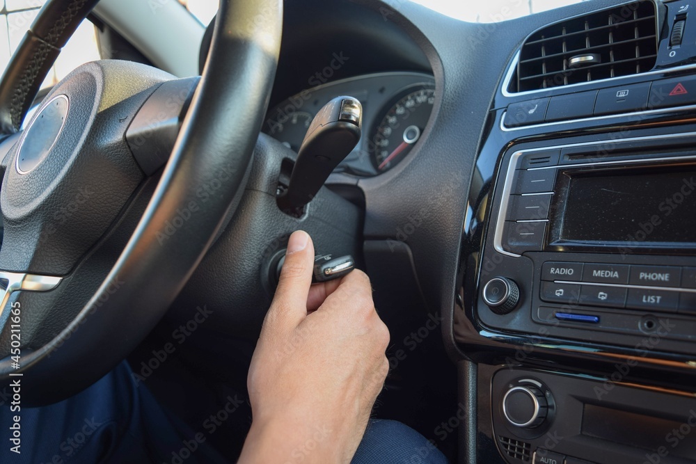 
The hand of the man, whose face is not visible, is on the ignition key in the car
