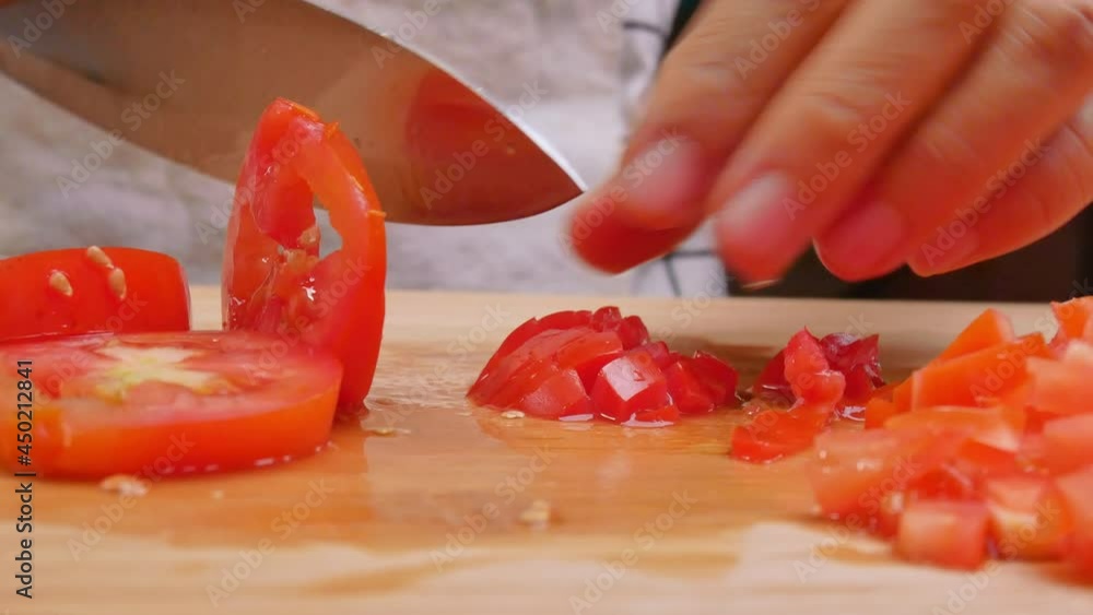 Female hands slices tomatoes on a wooden cutting board. Concept of preparing healthy meal. Female hands slices tomatoes on a wooden cutting board. Concept of preparing healthy meal.