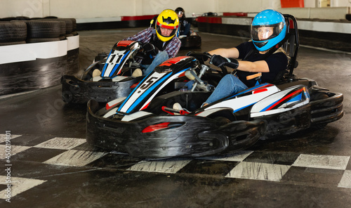 Young man and women competing on racing cars at kart circuit © JackF