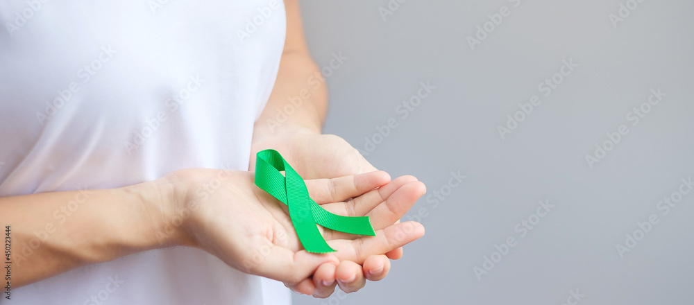 Hand holding green Ribbon for Liver, Gallbladders, bile duct, cervical, kidney Cancer and Lymphoma Awareness month. Healthcare and world cancer day concept Hand holding green Ribbon for Liver, Gallbladders, bile duct, cervical, kidney Cancer and Lymphoma Awareness month. Healthcare and world cancer day concept