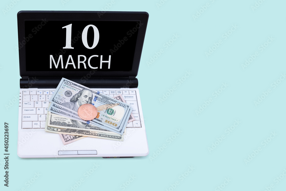 Laptop with the date of 10 march and cryptocurrency Bitcoin, dollars on a blue background. Buy or sell cryptocurrency. Stock market concept.