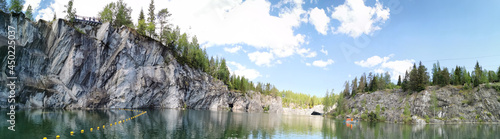 Panorama from the water to the steep slope of the flooded Marble Canyon in the Ruskeala Mountain Park on a sunny summer day.