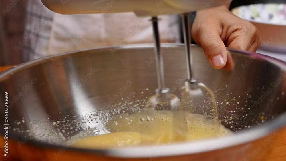 Female hands mixing sugar and eggs with an electric mixer prepared for homemade chocolate cookies or brownies. Step by step recipe for pastry. Female hands mixing sugar and eggs with an electric mixer prepared for homemade chocolate cookies or brownies. Step by step recipe for pastry.