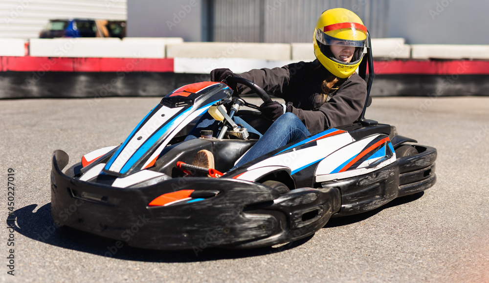 Portrait of girl in helmet driving kart at racing track outdoors