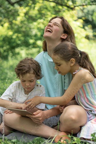 Children with a tablet outdoors. Children play games on the tablet. Technology concept.