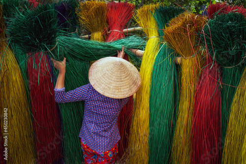 Back side of Vietnamese female craftsman drying traditional vietnam mats in the old traditional village at dinh yen, dong thap, vietnam, tradition artist concept photo
