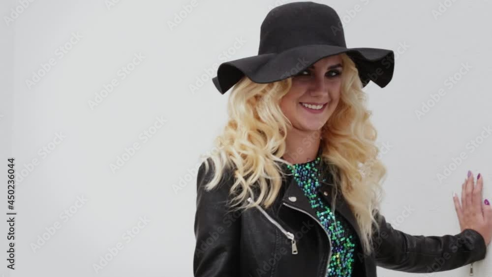 Beautiful blonde girl in a black hat and black leather jacket turns to the camera and shows her tongue Beautiful blonde girl in a black hat and black leather jacket turns to the camera and shows her tongue