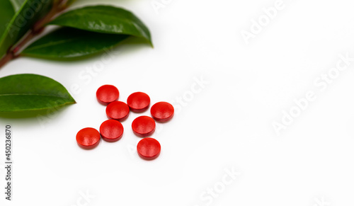 Red pills with leaves from fresh green source herbs in a display isolated on a white background.	 photo