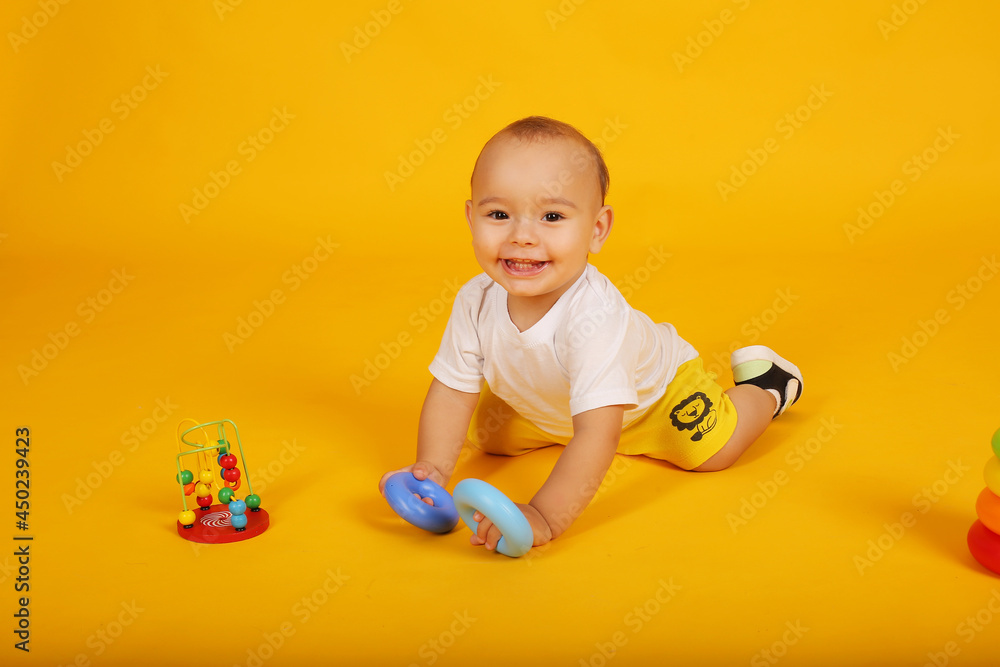a little boy in a white T-shirt and yellow shorts plays with blocks pyramid toys a little boy in a white T-shirt and yellow shorts plays with blocks pyramid toys