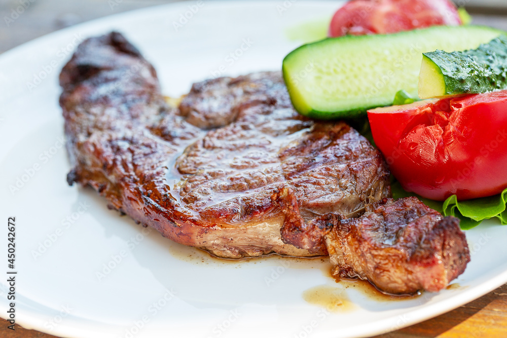 Beef steak with vegetables on a white plate.   Selective focus