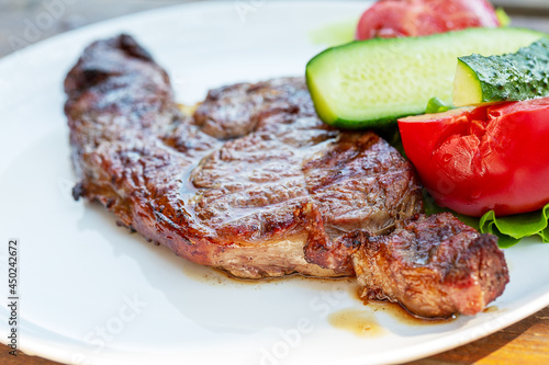 Beef steak with vegetables on a white plate.   Selective focus