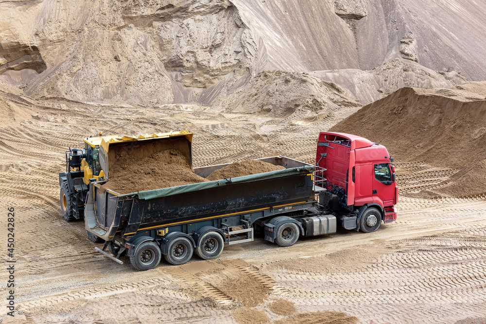 Obraz premium A loader loads sand into the car body in a sand quarry