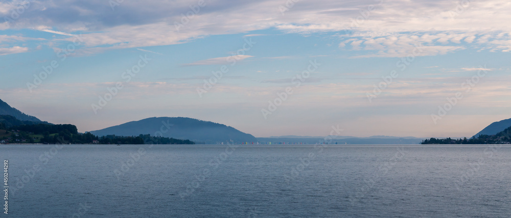 Panoramic view to lake attersee at morning cloudy sky with small sailboat ship. Austria, salzburg