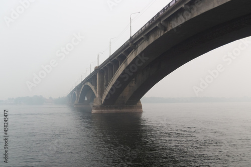 Cityscape with a Bridge Communal over the Yenisei river in Krasnoyarsk hidden in the heavy smog due to forest fires. Black sky mode in the city. Ecological catastrophe