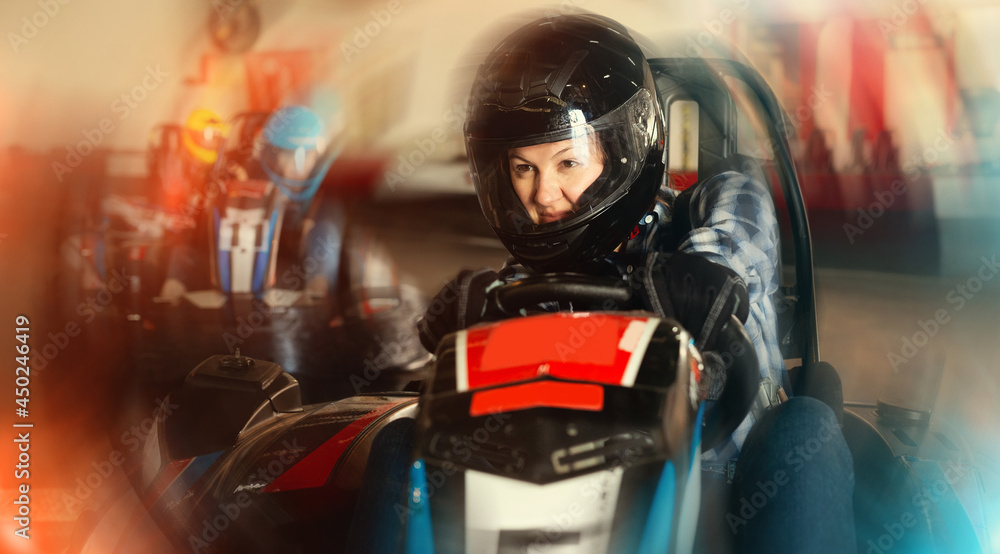 young happy woman driving racing car at kart circuit