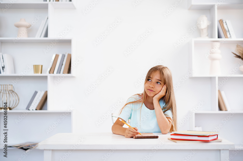 Teenage girl making notes in notepad, doing homework at table at home Teenage girl making notes in notepad, doing homework at table at home