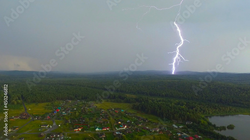 Powerful lightning strikes the ground. Aerial view of the village during the stormy season