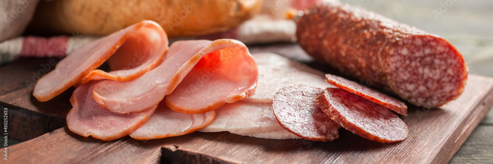 Set of various cut sausages on cutting board. Banner