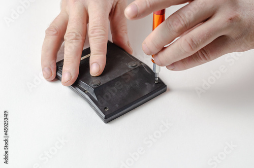 Hands, screwdriver, calculator on white background. Man disassem