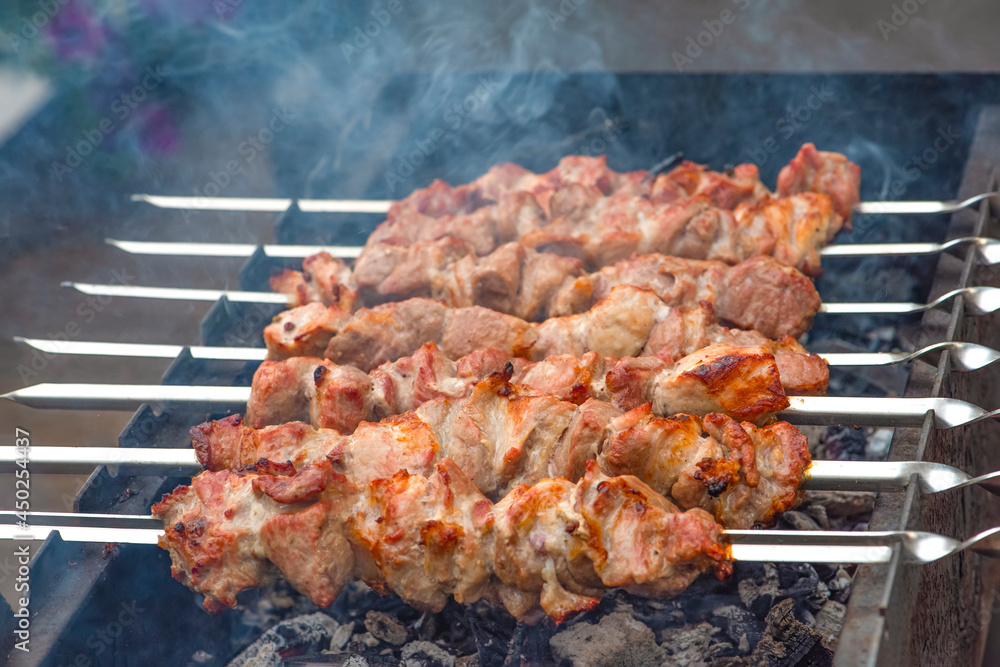 Grilled pork meat on metal skewers. Barbecue cooking. The smoke from the coals develops over the meat. Promotional banner for menu with copy space to insert text