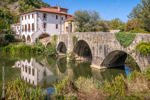 View of Medieval Bridge over the River Ulzama and Adjacent Basilica and Pilgrim Albergue Hostel on the Way of St James Pilgrimage Trail Camino de Santiago photo