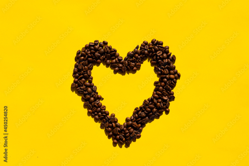Top view heart-shaped coffee beans on a yellow background