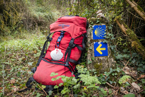 Pilgrim Backpack Gear and Way Marking Post with Yellow Arrow and Scallop Shell Sign on the Pilgrimage Trail Way of St James Camino de Santiago outside Zuriain, Navarra Spain