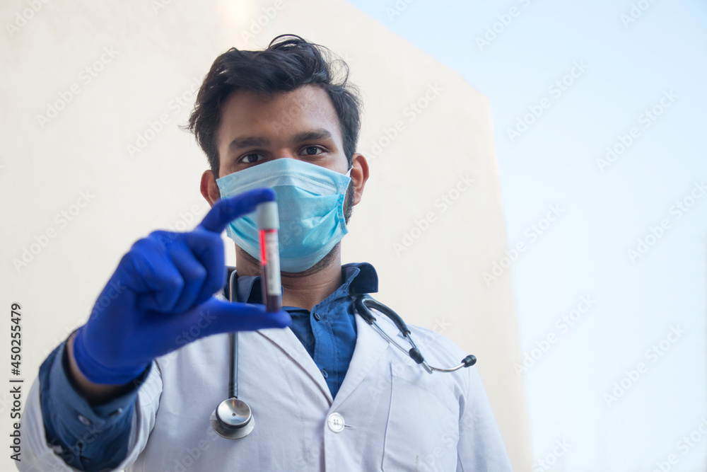 A doctor wearing face mask analyzing a blood sample A doctor wearing face mask analyzing a blood sample