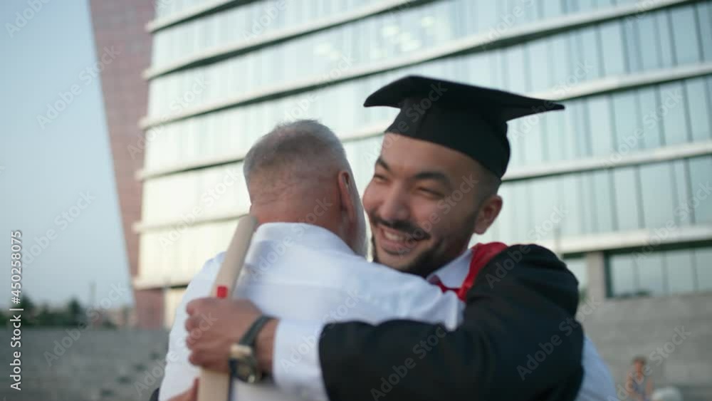 Graduation, a father embraces his son, a university graduate, young man in a graduate's robe holds a diploma in her hands, an emotional moment, 4k slow motion. Graduation, a father embraces his son, a university graduate, young man in a graduate's robe holds a diploma in her hands, an emotional moment, 4k slow motion.