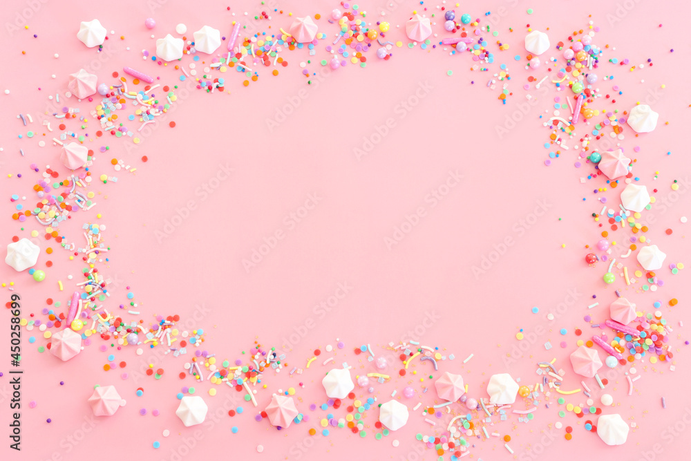 Party colorful candies and meringue over pastel pink background. Top view, flat lay