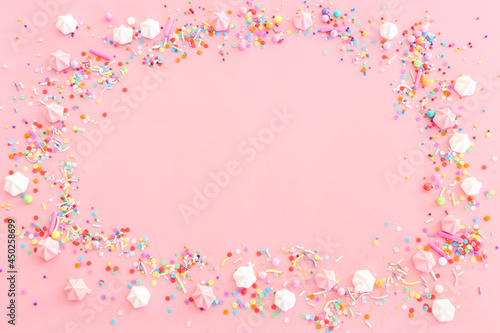 Party colorful candies and meringue over pastel pink background. Top view, flat lay