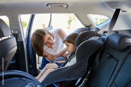 Mum putting daughter in child car seat