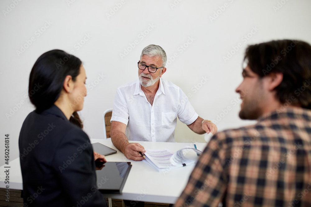 Three business people sitting at a desk, talking in a studio Three business people sitting at a desk, talking in a studio