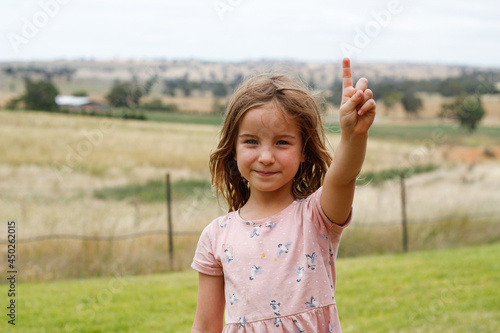 Young girl in pink dress pointing skyward photo