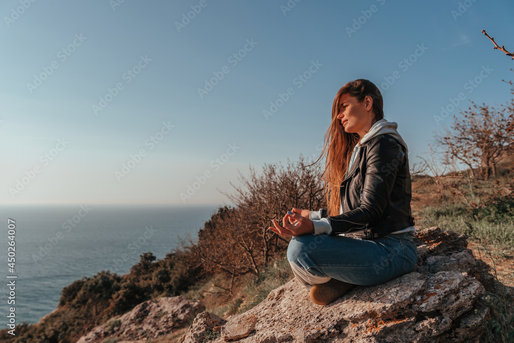 A young tourist Woman enjoying sunset over sea mountain landscape while sitting outdoor. Women's yoga fitness routine. Healthy lifestyle, harmony and meditation