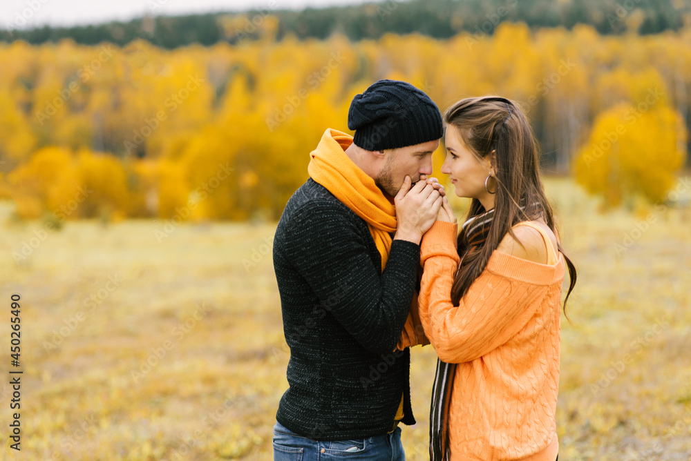A guy warms the palms of his beloved girl against the background of the autumn landscape. Fall trip at the weekend A guy warms the palms of his beloved girl against the background of the autumn landscape. Fall trip at the weekend
