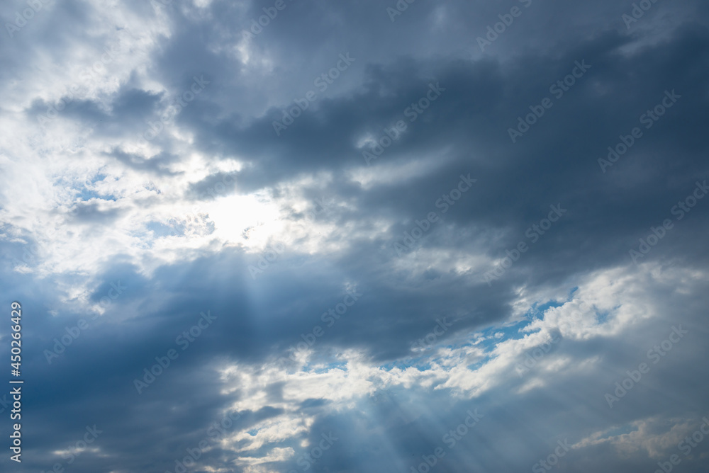 Dramatic blue sky with clouds and sun rays.Summer Sun rays at sunset.