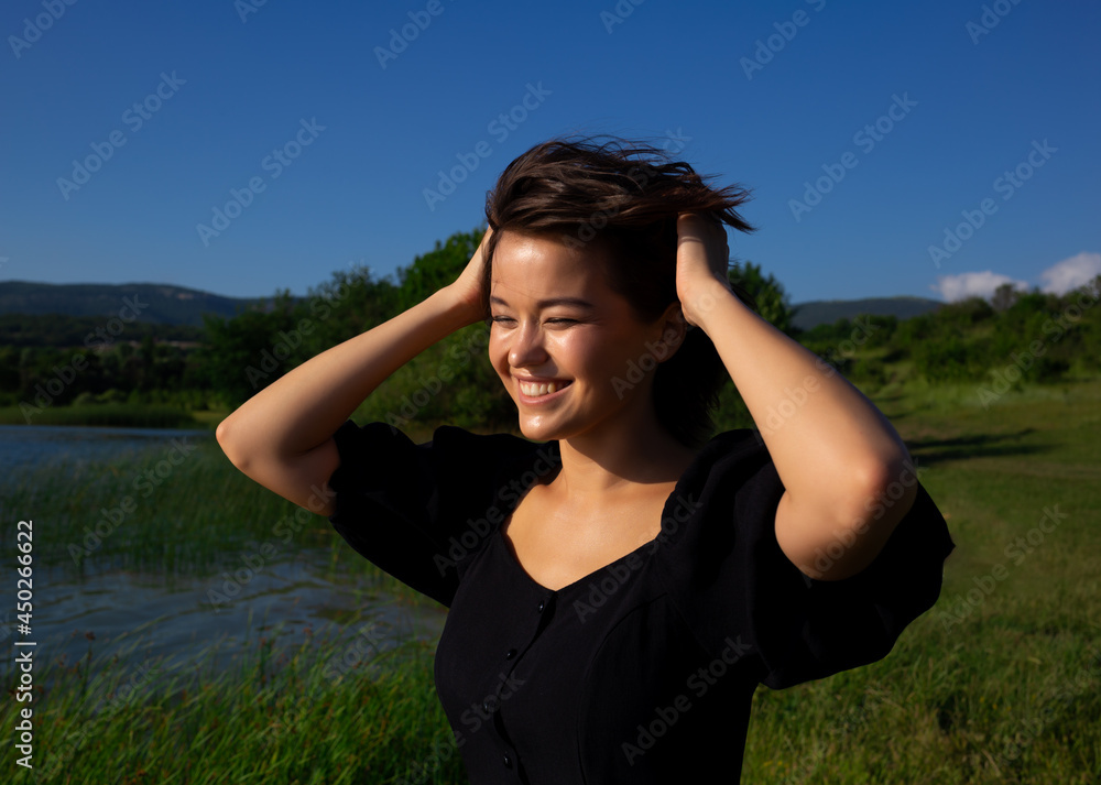 portrait of a young asian woman on the background of meadow and lake