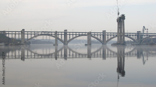 Lustrzane odbicie budowy mostu przez rzekę Dniepr w Zaporożu, Ukraina photo