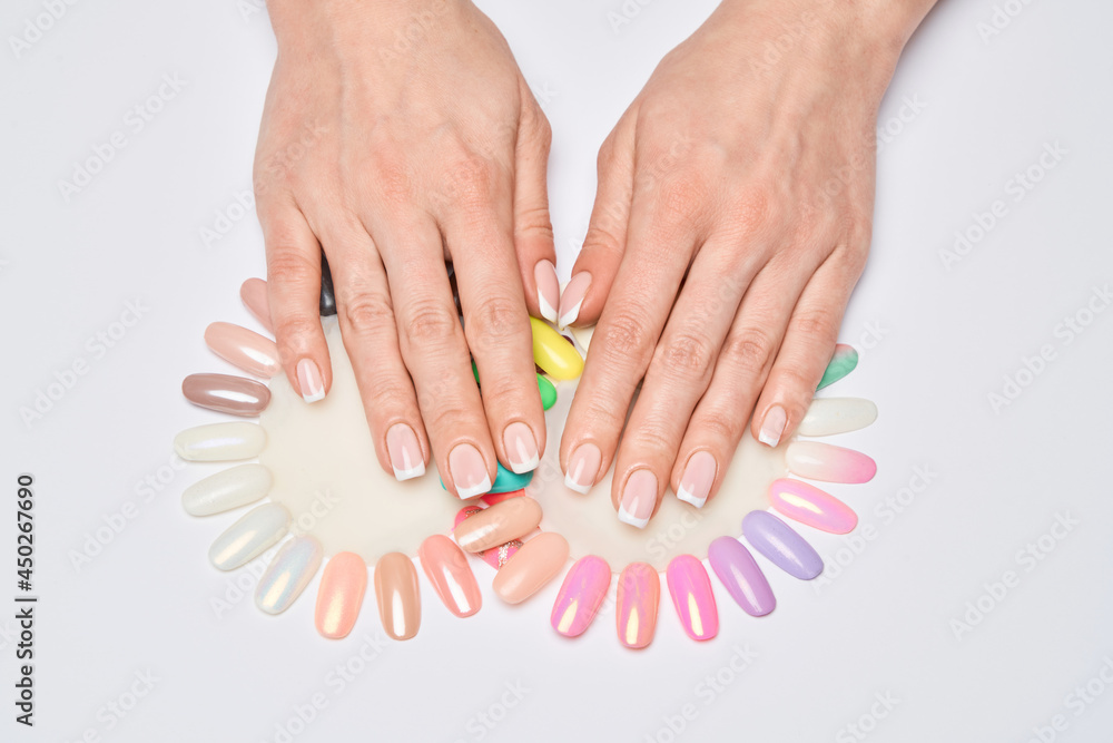 woman with well-groomed hands and healthy nails holding palette with swatches collection of nail Polish for manicure woman with well-groomed hands and healthy nails holding palette with swatches collection of nail Polish for manicure