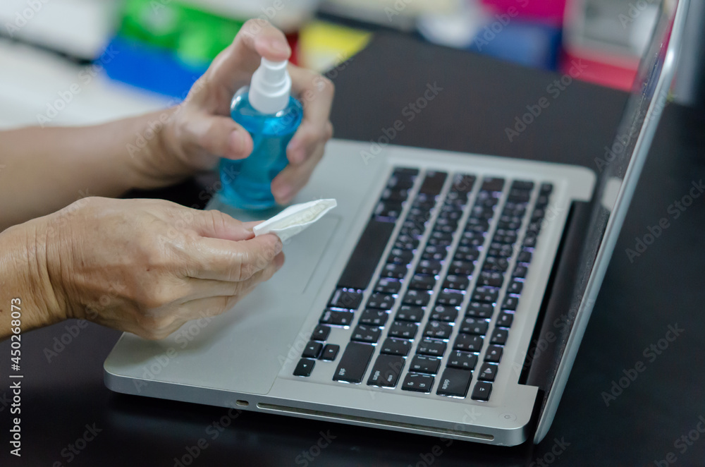 Spraying alcohol to clean the computer and wipe the germs. Health care concept. Spraying alcohol to clean the computer and wipe the germs. Health care concept.