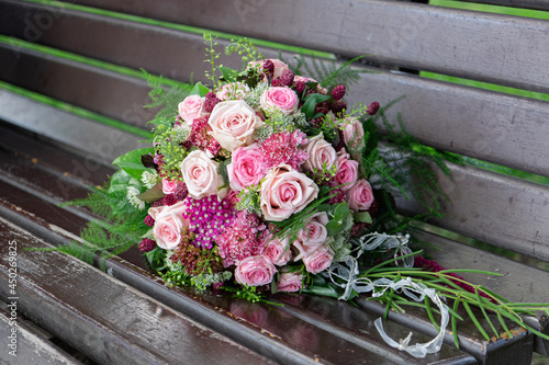 a bridal's bouquet of pink roses on a park bench