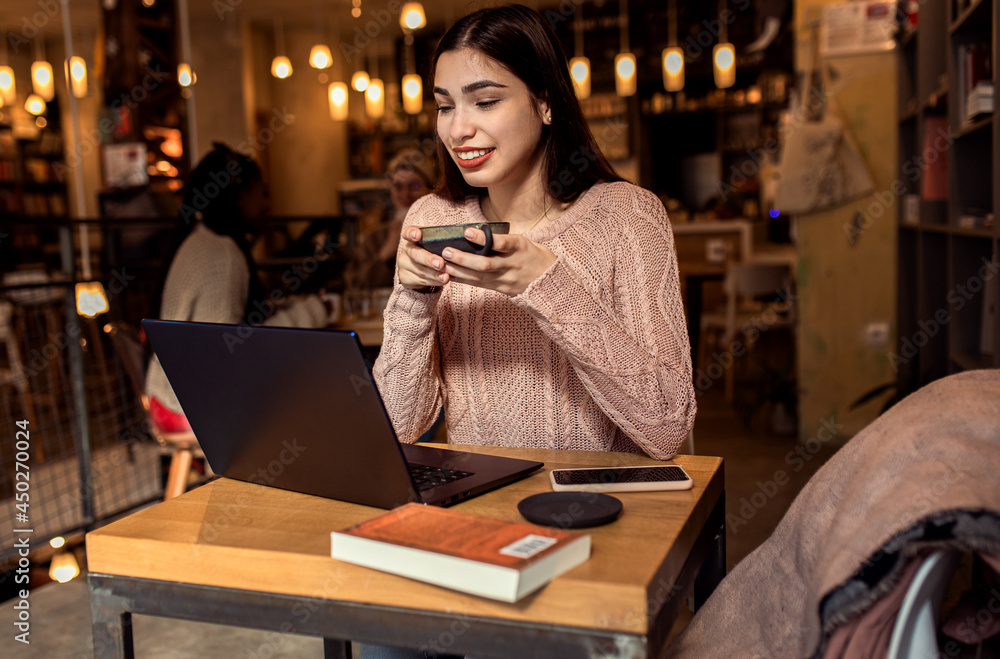 Portrait of young woman working on using laptop at coffee shop. Portrait of young woman working on using laptop at coffee shop.
