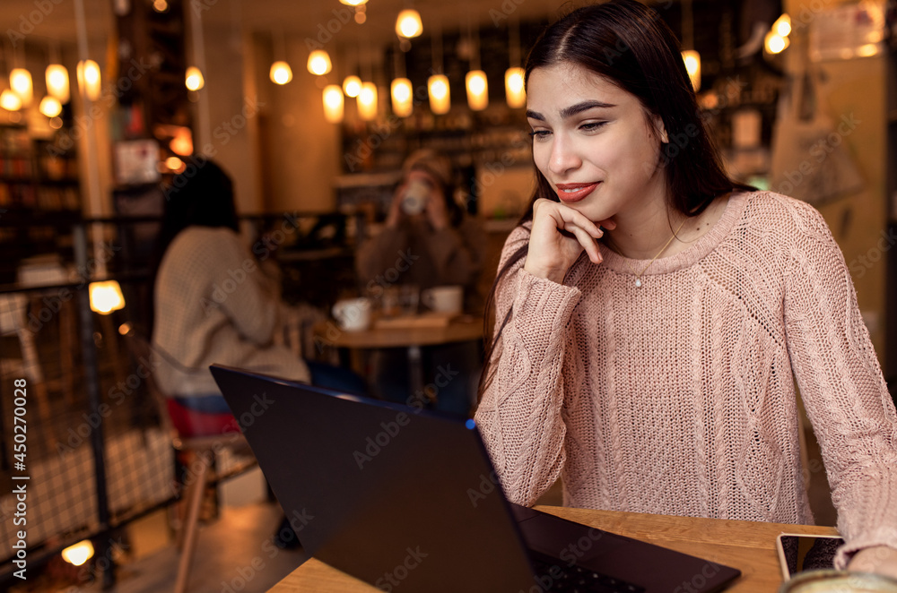 Portrait of young woman working on using laptop at coffee shop. Portrait of young woman working on using laptop at coffee shop.